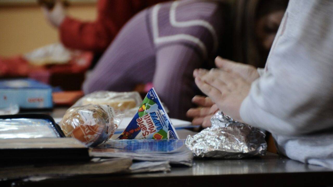 o persoana care sta in banca si niste alimente pe masa